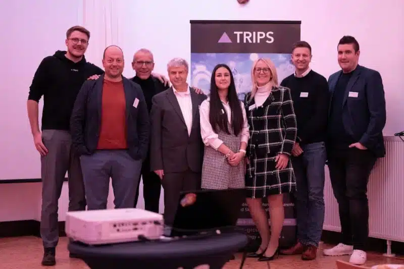 Männer und Frauen vor TRIPS-Logo bei Feier 15 Jahre Wülfrath | TRIPS group