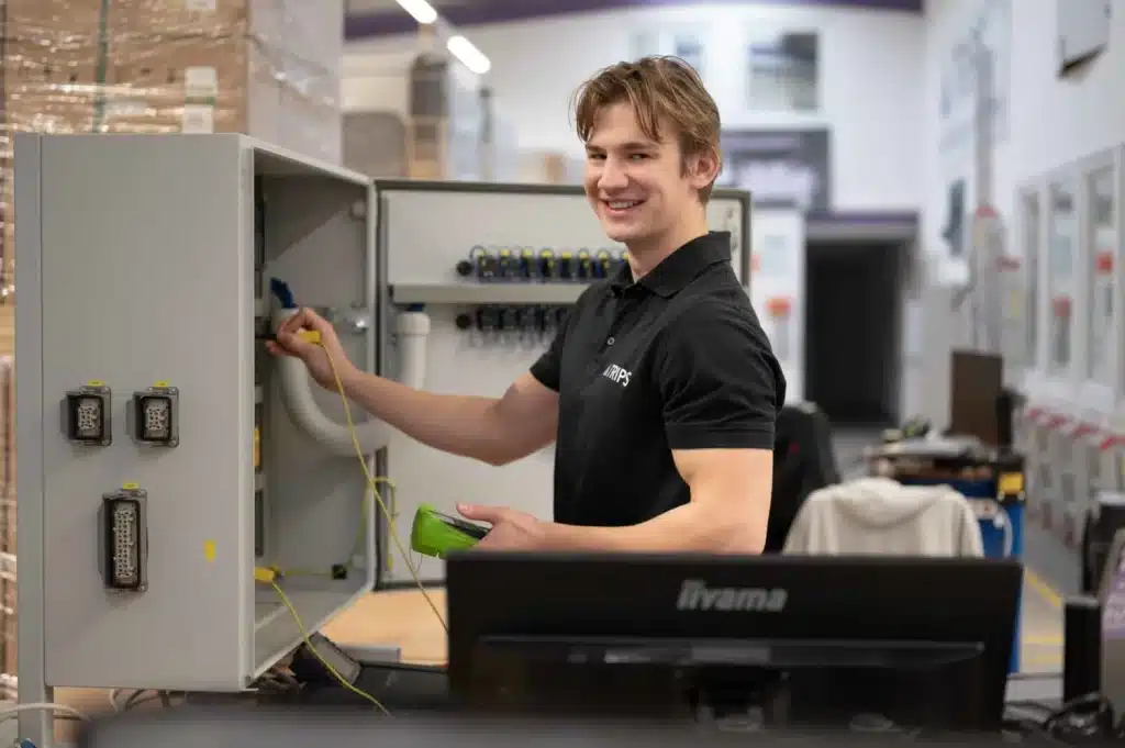 TRIPS-Mitarbeiter in Produktionshalle mit Schaltschrank | TRIPS group